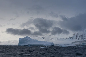 Iceberg in a fjord with mountain scenery and a cloudy sky, Gerlache Strait Iceberg in a fjord with mountain scenery and a cloudy sky, Gerlache Strait