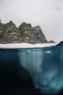 <b class=qtipBold><figcaption>Iceberg and Rock Face</figcaption></b><br>Split level image showing a small iceberg underwater and a mountainous rock face located in Scoresbysund Fjord on the east coast of Greenland.<br><em>© 2016 Wildestanimal</em> Iceberg and Rock Face