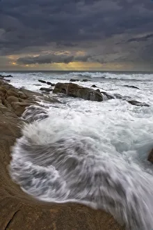 Landscape photo of ocean waves crashing onto the rocks under a stormy moody sky at sunrise Landscape photo of ocean waves crashing onto the rocks under a stormy moody sky at sunrise