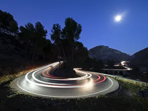 Lights of vehicles in movement circulating along a carretera with curves very closed in the moonlight Lights of vehicles in movement circulating along a carretera with curves very closed in the moonlight