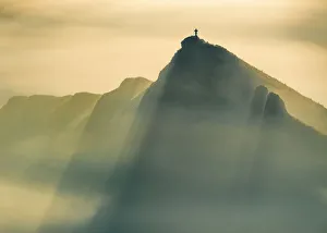 A Lone man stands on a jagged hill in misty conditions at sunrise, English Peak District A Lone man stands on a jagged hill in misty conditions at sunrise, English Peak District