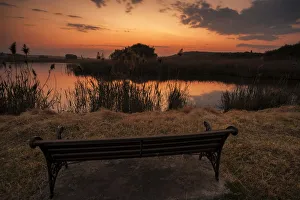 Lonesome bench landscape at sunset on the shore of a remote farm lake, Magaliesburg Lonesome bench landscape at sunset on the shore of a remote farm lake, Magaliesburg