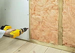 Man drilling screws in plasterboard and batten to hide insulation, close-up Man drilling screws in plasterboard and batten to hide insulation, close-up