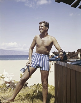 Man holding snorkel and flippers on beach, smiling Man holding snorkel and flippers on beach, smiling