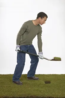 Man holding a spade with section of turf on the blade Man holding a spade with section of turf on the blade