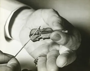 Man holding tiny violin, close up of hands Man holding tiny violin, close up of hands