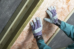Man installing roof insulation in rafter, close-up Man installing roof insulation in rafter, close-up