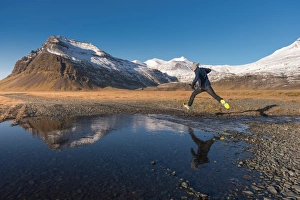 a man jumping across a water with snow mountain background a man jumping across a water with snow mountain background