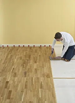 Man kneeling and holding hammer over floorboards Man kneeling and holding hammer over floorboards