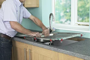 Man placing a new sink in to position in a worktop Man placing a new sink in to position in a worktop
