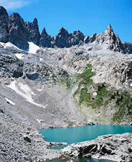Man on shore of alpine lake with mountain peaks Man on shore of alpine lake with mountain peaks