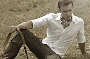 Man wearing riding clothes sitting in a field in summer Man wearing riding clothes sitting in a field in summer