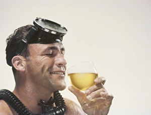 Man wearing snorkel holding wine glass, smiling Man wearing snorkel holding wine glass, smiling