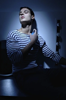 Man wearing a striped T-shirt in a bathroom, spraying on perfume Man wearing a striped T-shirt in a bathroom, spraying on perfume