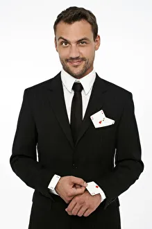 Man wearing a suit pulling an ace of diamonds out of his sleeve with other aces in Man wearing a suit pulling an ace of diamonds out of his sleeve with other aces in