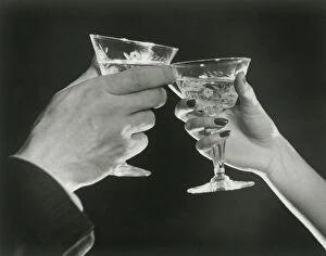 Man and woman toasting martini glasses, close up of hands