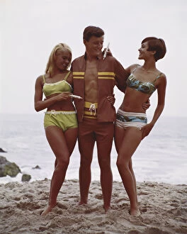 Bikini Gallery: Man with two women standing on beach, smiling