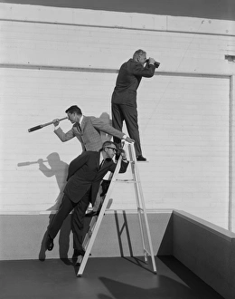Men standing on ladder with binoculars and telescope Men standing on ladder with binoculars and telescope