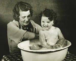 Mother bathing daughter (12-18 months) in basin, (B&W) Mother bathing daughter (12-18 months) in basin, (B&W)