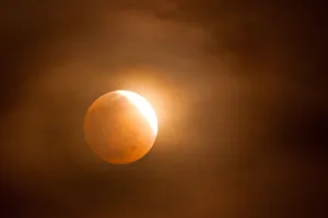 <b class=qtipBold><figcaption>Orange Glow Lunar Eclipse</figcaption></b><br>Lunar eclipse seen from Ewa Beach, Oahu, Hawaii, April 14, 2014. Orange tinted Moon shrouded in clouds displays a bright glowing edge. The night sky is dark and starless.<br><em>© 2014 Kjell Suwardi Linder</em> Orange Glow Lunar Eclipse