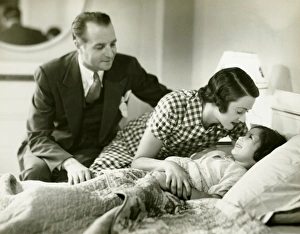 Parents tucking daughter (6-7) into bed, (B&W) Parents tucking daughter (6-7) into bed, (B&W)