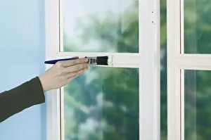 Person painting window frame with a brush Person painting window frame with a brush
