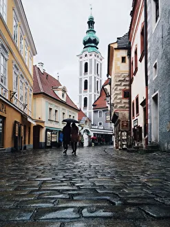 Two persons with one umbrella wandering in the cobbled streets in the old town of Cesky Two persons with one umbrella wandering in the cobbled streets in the old town of Cesky