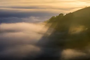 Peveril Castle shadows above the golden fog at sunrise. English Peak District. UK Peveril Castle shadows above the golden fog at sunrise. English Peak District. UK