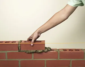 Placing a new brick on to fresh mortar on a wall Placing a new brick on to fresh mortar on a wall