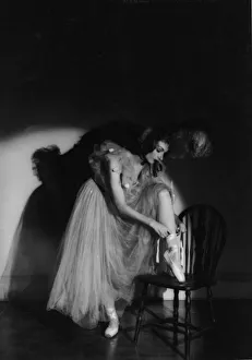 <b class=qtipBold><figcaption>Putting On Pointe Shoes</figcaption></b><br>Studio portrait of a ballerina in a long tulle dress and ornate headdress tying the ribbon of her pointe shoe, her image silhouetted by a spotlight, 1930s. (Photo by FPG/Getty Images)<br><em>© 2005 Getty Images</em> Putting On Pointe Shoes