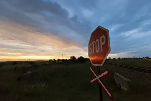 Railway crossing warning signal with Stop sign at sunset near the town of Magaliesburg Railway crossing warning signal with Stop sign at sunset near the town of Magaliesburg