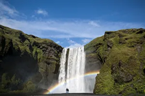 Rainbow, couple watching the Skogafoss waterfall on the Skoga river, ring road, Suourland Rainbow, couple watching the Skogafoss waterfall on the Skoga river, ring road, Suourland