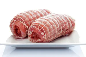 Raw pork roulade in a net on a porcelain plate Raw pork roulade in a net on a porcelain plate