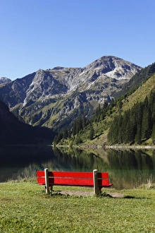 Red bench on Lake Vilsalpsee at Tannheim, Vilsalpseeberge mountains Red bench on Lake Vilsalpsee at Tannheim, Vilsalpseeberge mountains