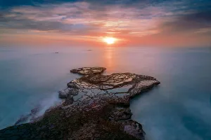 A rocky outcrop reaching out to the sun peeping through the clouds at Arniston with a A rocky outcrop reaching out to the sun peeping through the clouds at Arniston with a