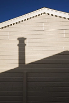 Roofline and chimney shadow on the exterior side wall of a residential home, Quebec, Canada Roofline and chimney shadow on the exterior side wall of a residential home, Quebec, Canada