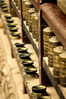 A row of prayer mills and butter lamps in the Golden Temple, a Buddhist temple, Patan A row of prayer mills and butter lamps in the Golden Temple, a Buddhist temple, Patan