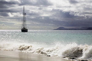 Sailing boat on the Playa de Mujeres beach near Playa Blanca, Fuerteventura in the back Sailing boat on the Playa de Mujeres beach near Playa Blanca, Fuerteventura in the back