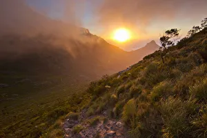 Scenic sunset over Table Mountain and Lions Head as seen from a hiking trail up Devils Scenic sunset over Table Mountain and Lions Head as seen from a hiking trail up Devils