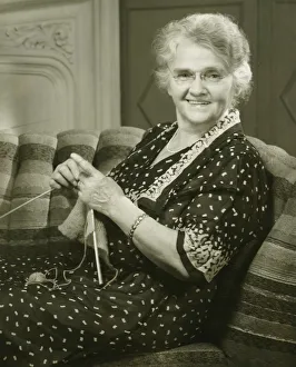 Senior woman knitting in living room, (B&W), portrait Senior woman knitting in living room, (B&W), portrait