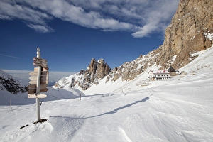 Signpost, Tierser Alplhutte mountain cabin and Rosszahne peaks in winter, Seiser Alm alp Signpost, Tierser Alplhutte mountain cabin and Rosszahne peaks in winter, Seiser Alm alp