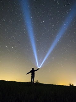Silhouette of a man doing signs with a lantern on the horizon in the night Silhouette of a man doing signs with a lantern on the horizon in the night