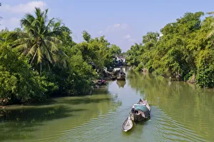 Small wooden motorboat passing through a water channel surrounded by tropical vegetation, Hue, Vietnam, Asia Small wooden motorboat passing through a water channel surrounded by tropical vegetation, Hue, Vietnam, Asia