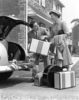 Images Dated 10th February 2006: Smiling couple load suitcases into trunk of sedan