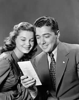 Images Dated 10th February 2006: Smiling couple looking at insurance policy brochure