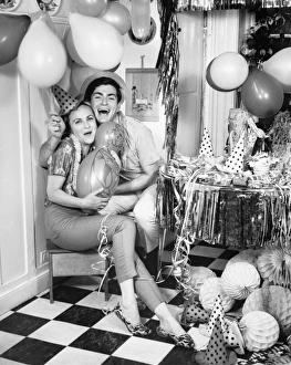 Smiling couple sitting in kitchen amongst party preparations, (B&W), portrait Smiling couple sitting in kitchen amongst party preparations, (B&W), portrait