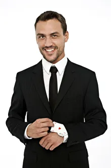 Smiling man wearing a suit pulling several aces out of his sleeve Smiling man wearing a suit pulling several aces out of his sleeve