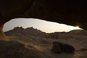 <b class=qtipBold><figcaption>Spitzkoppe, Namibia</figcaption></b><br>Sunrise over the bald granite peaks of the Pondok Mountains, framed by a rock arch. Located between Usakos and Swakopmund in the Namib desert. Sunrise.<br><em>© BenCranke</em> Spitzkoppe, Namibia