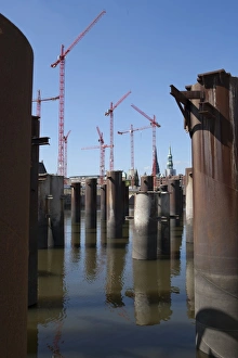 Steel pillars in the water in front of construction cranes in the new development area of Steel pillars in the water in front of construction cranes in the new development area of