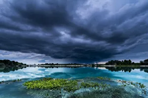 Storm clouds over a quarry lake with water plants, near Mindelheim, Unterallgau, Allgau Storm clouds over a quarry lake with water plants, near Mindelheim, Unterallgau, Allgau